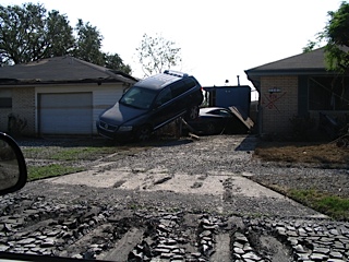 Driveway damaged with car overturned onto house